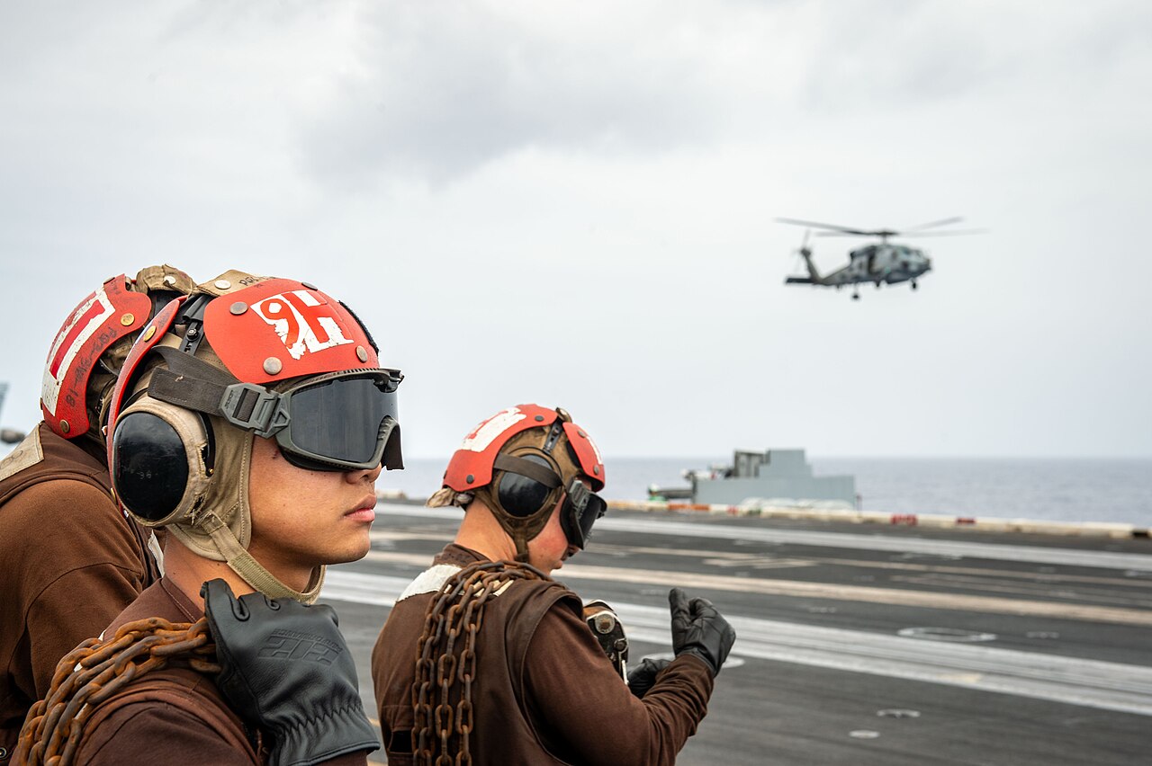 Personal de cubierta y un helicóptero durante operaciones de vuelo a bordo del USS Theodore Roosevelt.