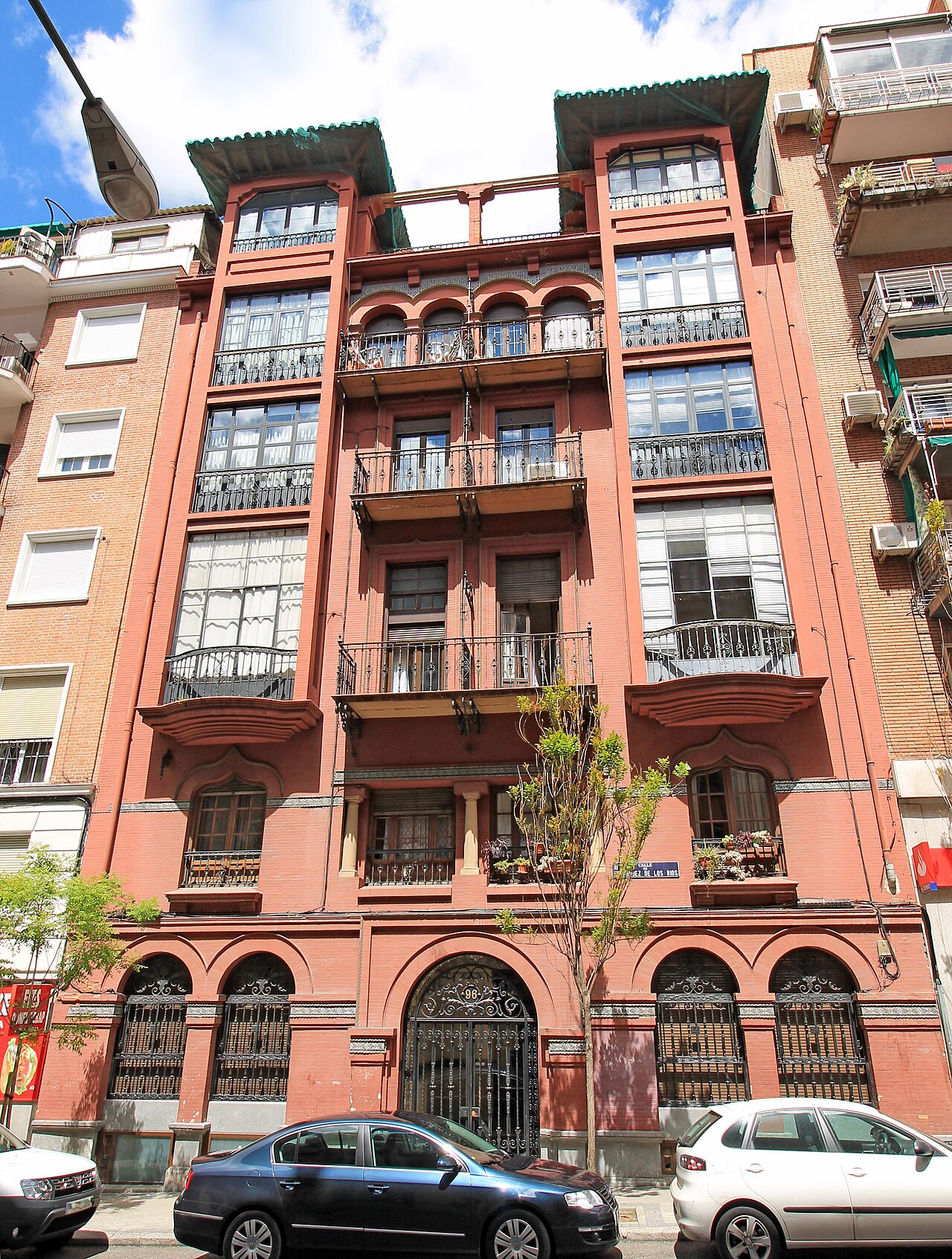 Fachada de ladrillo rojo de un edificio de viviendas con balcones en Madrid.